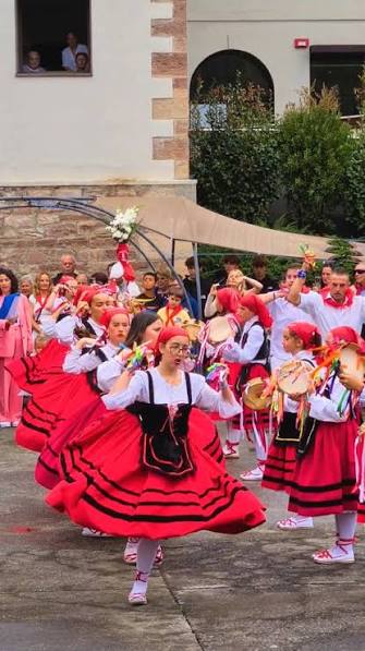Grupo de picayos con traje tradicional pasiego tocando pandereta y silbo en una fiesta popular de Cantabria
