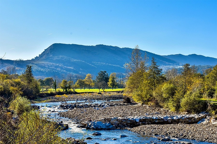 Vista general del valle del Saja con Cabezón de la Sal al fondo, prados verdes y sierra, luz de verano