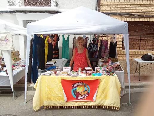 Puesto de ropa de lino y complementos boho colgados en un mercadillo de verano al aire libre