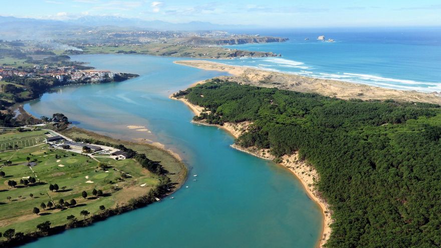 Playa tranquila de arena junto a una ría en la costa de Trasmiera, Cantabria, con marea baja y pocas personas