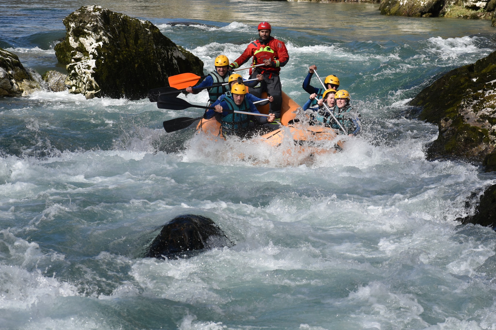Grupo remando una balsa de rafting entre aguas bravas y paredes de roca vertical en el Desfiladero de la Hermida.