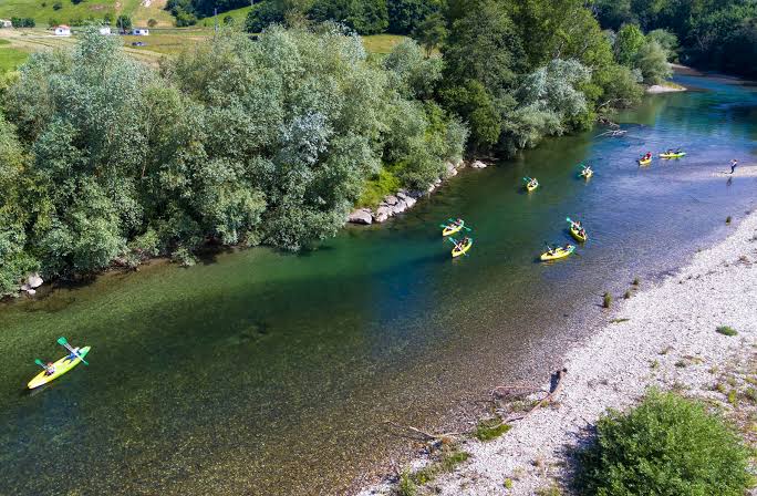 Dos personas remando una canoa por aguas tranquilas del río Deva entre paredes calizas, entre Panes y Unquera.
