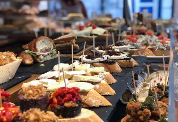 Barra de pinchos de La Esquina del Arrabal con clientes de pie, ambiente de barrio