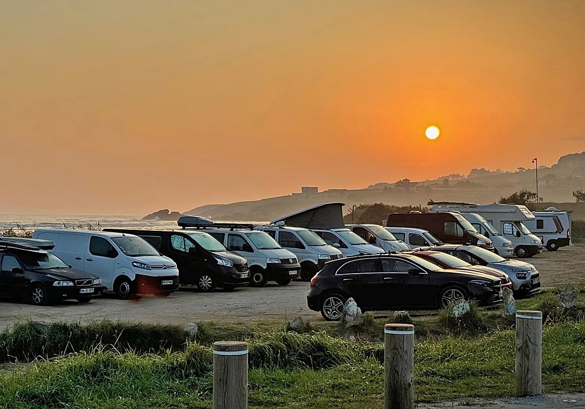 Aparcamiento junto a una playa de Cantabria lleno de coches en un día soleado de agosto