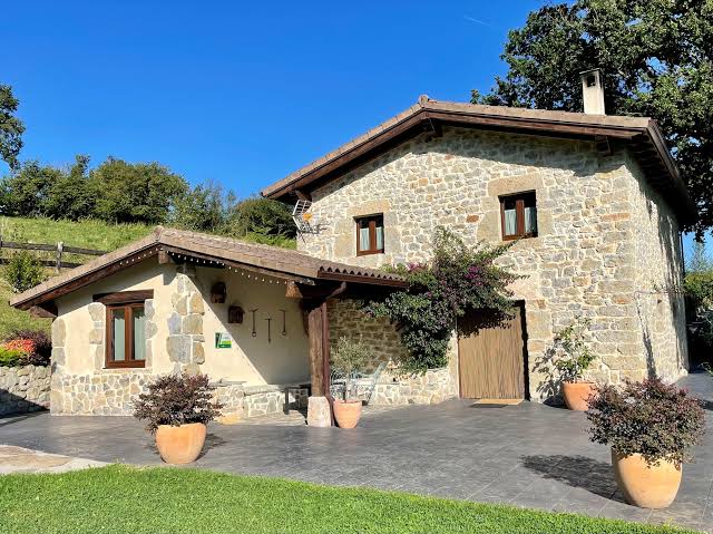 Fachada de una casa rural de piedra en Cantabria rodeada de vegetación