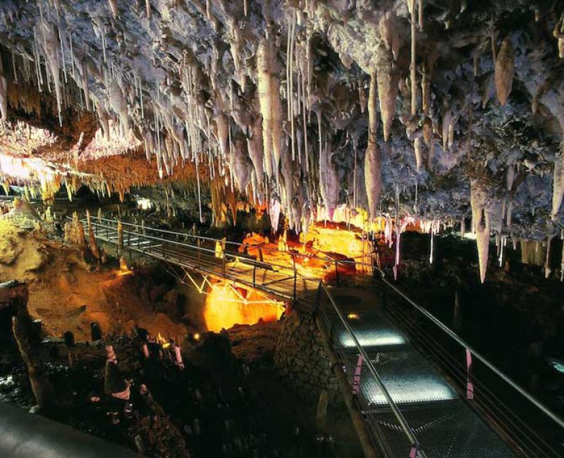 Interior de la Cueva El Soplao mostrando estalactitas y estalagmitas iluminadas en la penumbra, vista general de una galería