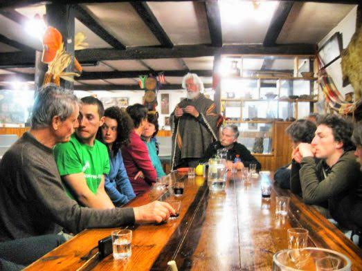 Mesa comunitaria del albergue de Güemes durante la cena, con peregrinos reunidos y luz cálida de interior