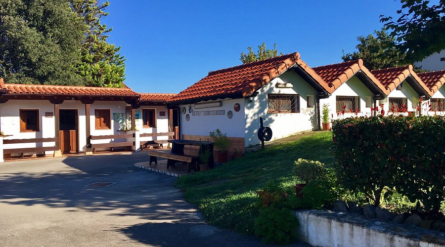 Fachada exterior de La Cabaña del Abuelo Peuto, el albergue de peregrinos de Güemes, con las cabañas de madera del jardín