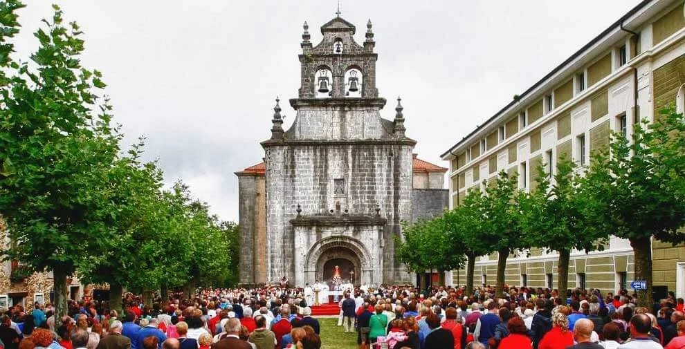 Comida campestre de la romería en el prado junto al santuario, familias con manteles y cestas de picnic