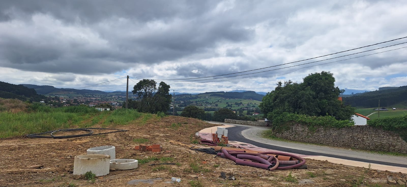 curva de acera y carretera terminada, casas y colinas al fondo
