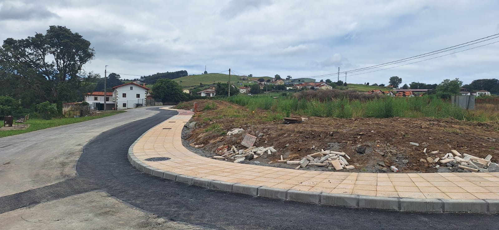 carretera asfaltada con la curva de acceso, farola y muro de piedra