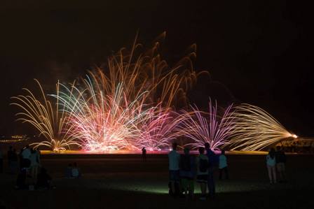 Fuegos artificiales nocturnos sobre la playa de Salvé en Laredo, vistos desde el paseo marítimo