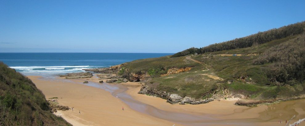Arena dorada y acantilados bajos de la playa de Galizano en marea baja