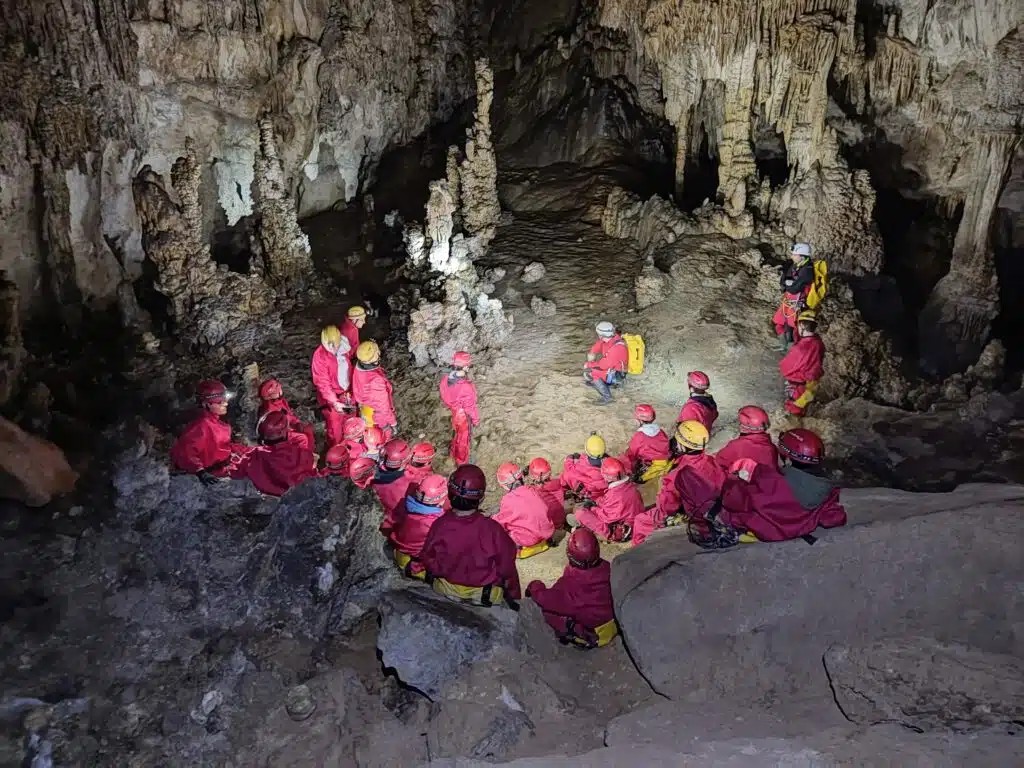 Grupo con casco y frontal entrando a una cueva guiado por VALCAN en el valle del Alto Asón