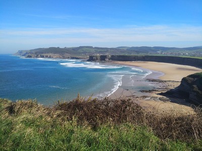 Vista aérea de la costa oriental de Cantabria, acantilados y arena dorada, luz de mañana