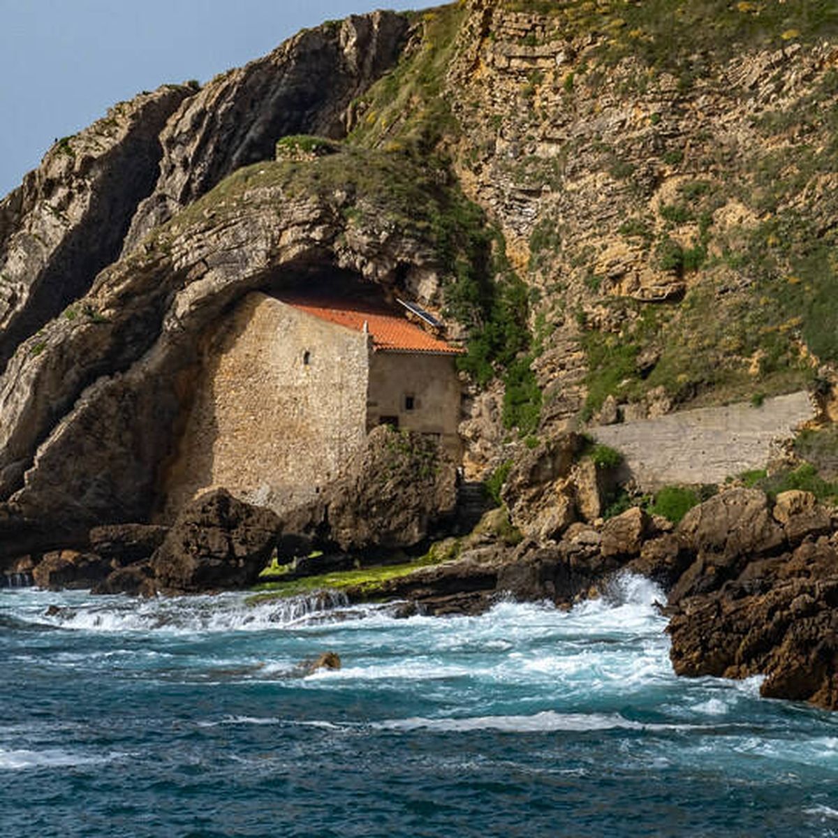 Ermita semiexcavada en el acantilado de la playa de Santa Justa en Ubiarco, con el mar al fondo