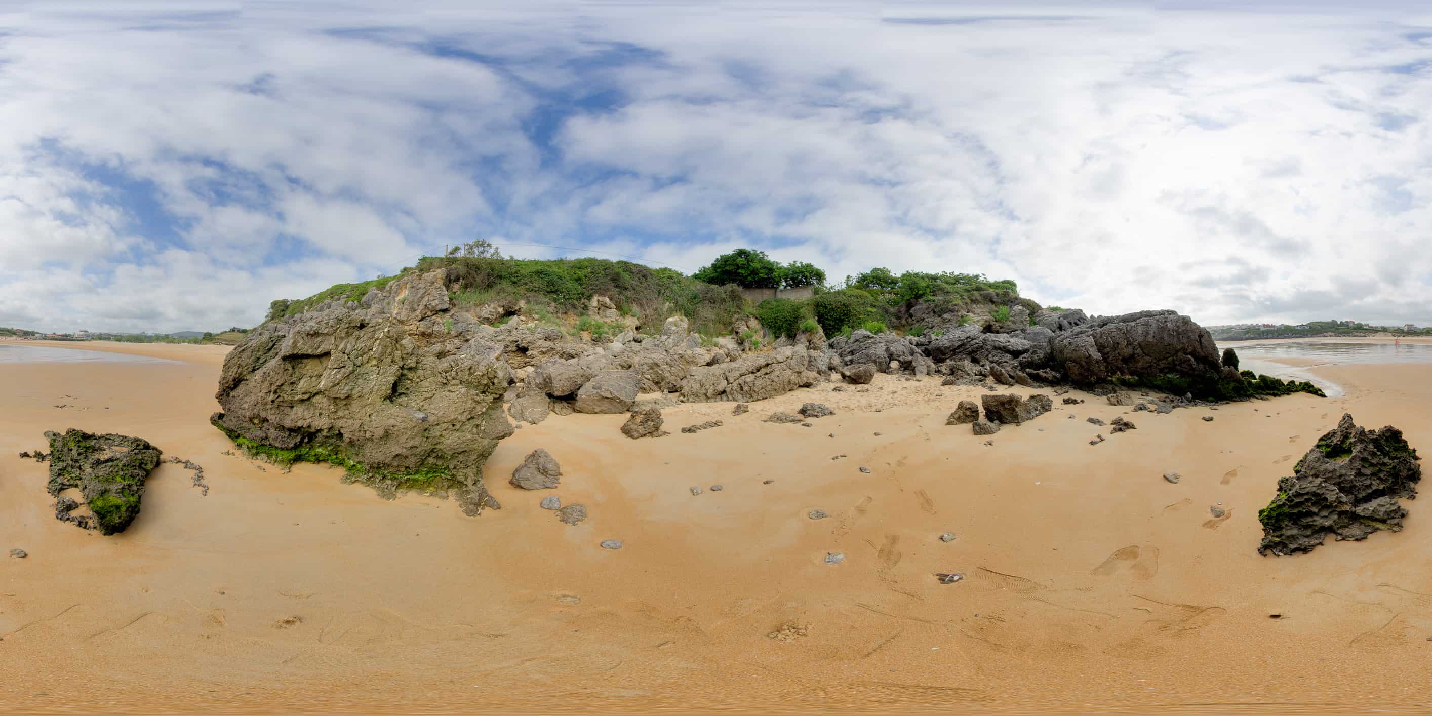Dunas protegidas con vegetación costera al fondo de la Playa de Ajo, primer plano de la arena
