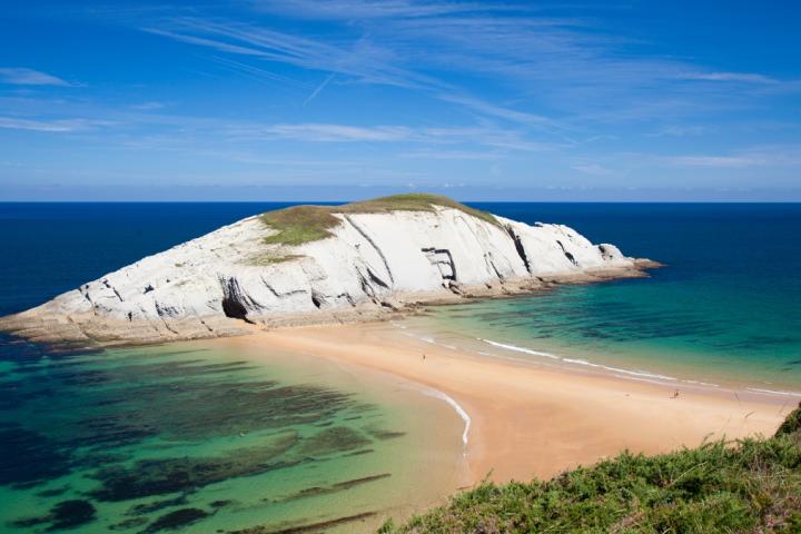 Tómbolo de arena de la Playa de Covachos uniendo la playa con la Isla de Castro en marea baja