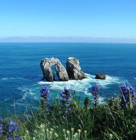 Arco natural de piedra de los Urros de Liencres enmarcando el mar Cantábrico al fondo