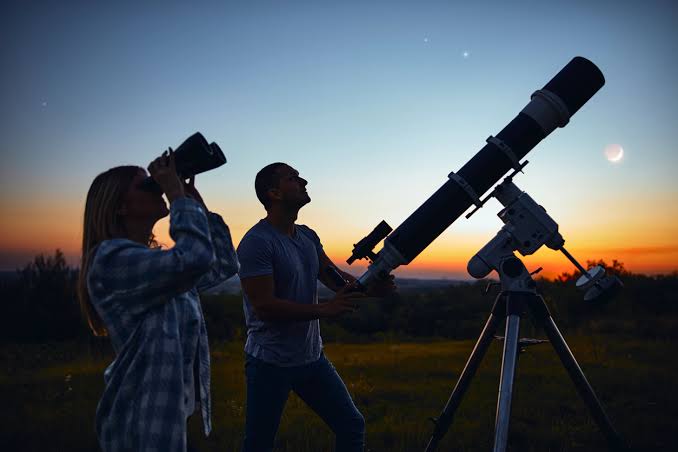 Grupo de personas observando el cielo con telescopios en una actividad de divulgación astronómica organizada por la Universidad de Cantabria.