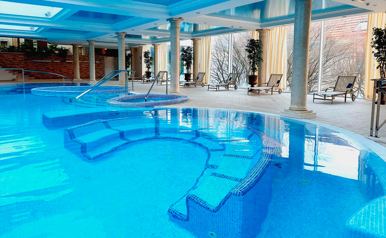 Piscina termal interior de un balneario con vapor sobre el agua, ambiente relajado.