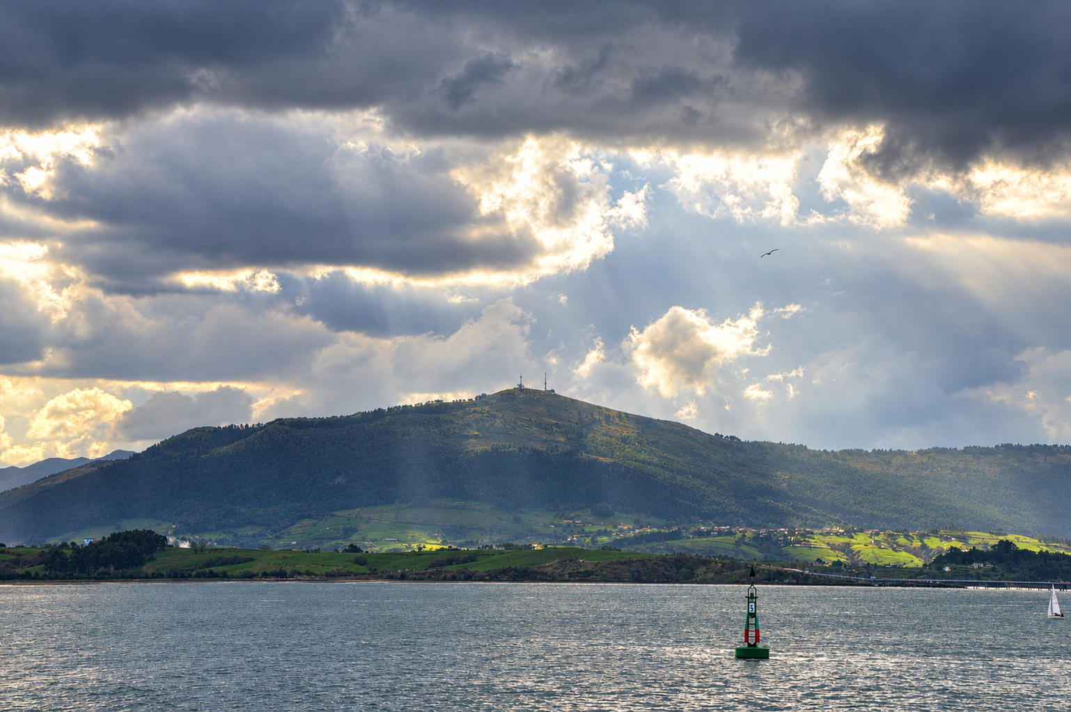 Vista de la bahía de Santander bajo un cielo nublado y lluvioso, con paraguas en primer plano.