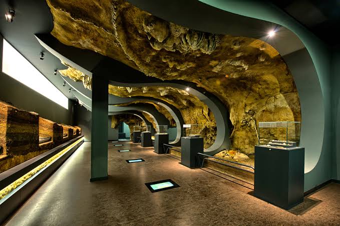 Vitrina de museo arqueológico con piezas prehistóricas iluminadas, sala interior.
