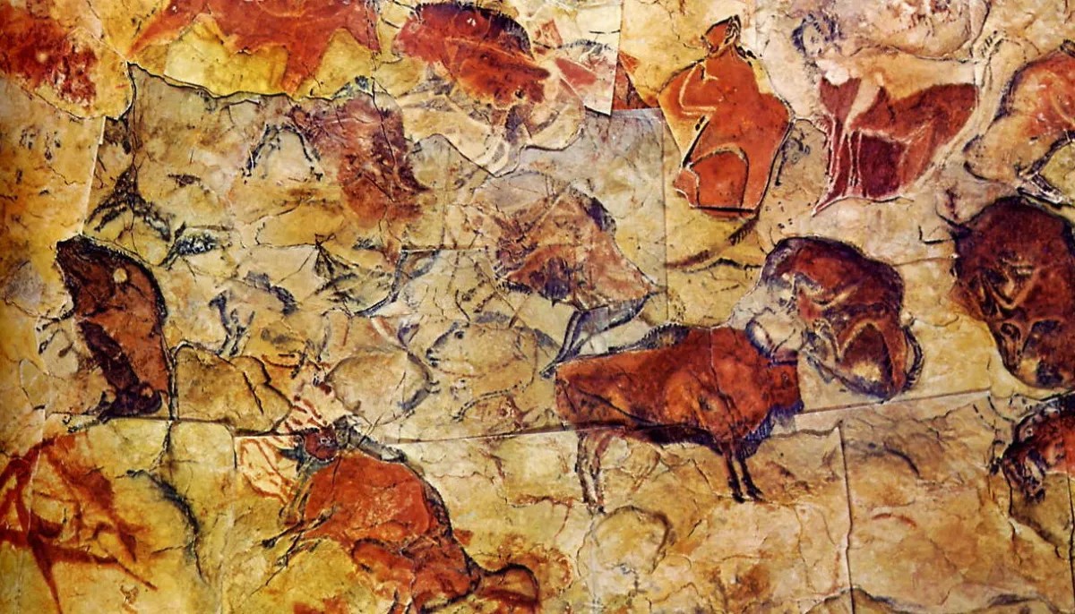 Réplica de pinturas rupestres de bisontes en el techo de una sala de museo en penumbra.