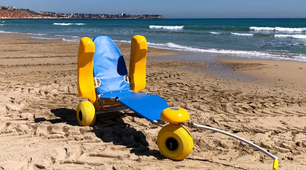Pasarela de madera de acceso a una playa cántabra con silla anfibia junto a la orilla