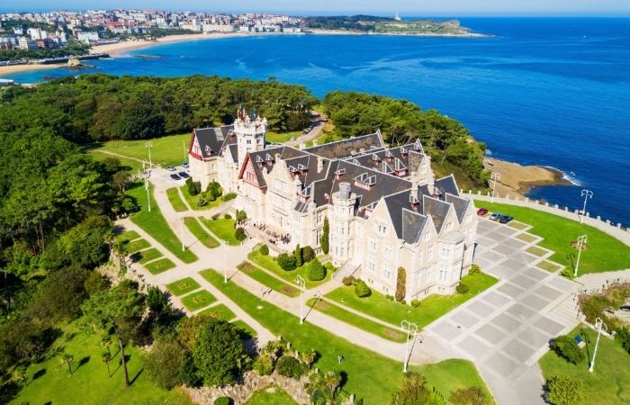 Playa amplia de Cantabria prácticamente vacía en temporada alta, familia paseando con espacio de sobra.