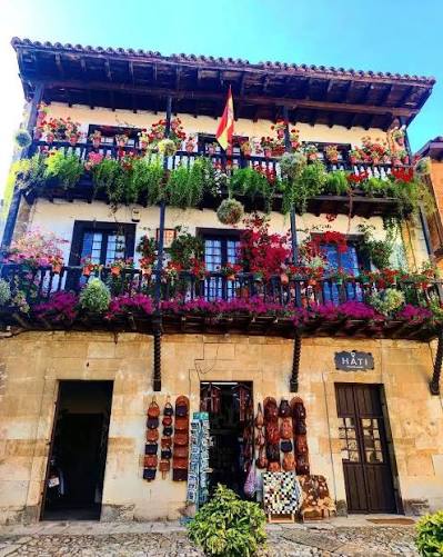 Calle empedrada de Santillana del Mar con casonas blasonadas y escudos nobiliarios tallados en piedra sobre las fachadas, a media mañana