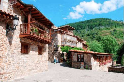 Solana de madera tallada con soportal de arcos de piedra en una casona barroca del valle del Saja-Nansa, Cantabria, luz de tarde