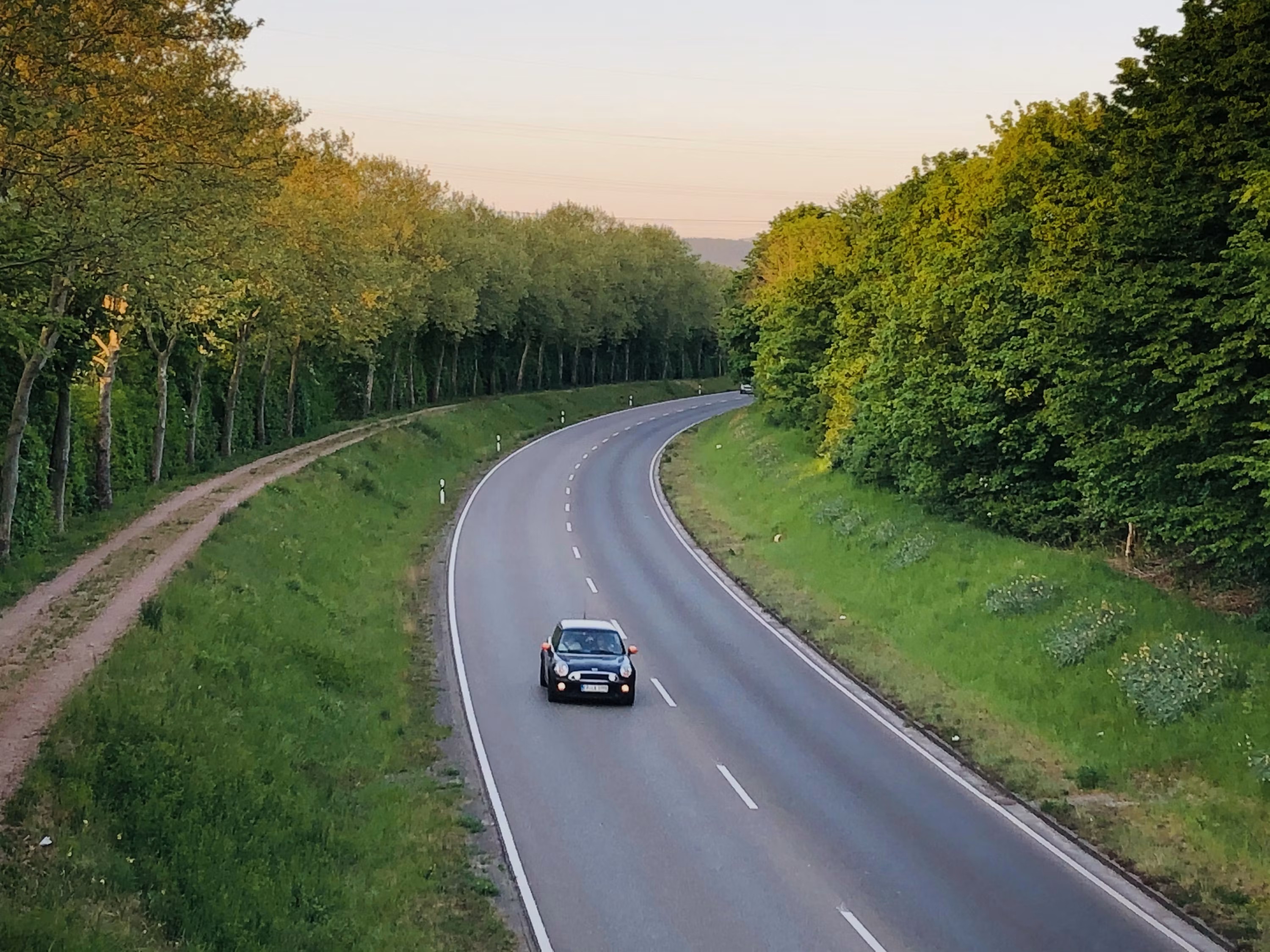 Carretera costera de la Trasmiera cerca de Bareyo con marismas y campo verde a ambos lados, sin tráfico, luz de atardecer.