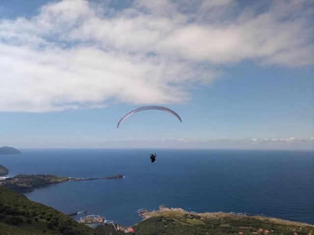 Parapente biplaza en pleno vuelo sobre el despegue de Islares, con la costa y el mar de fondo