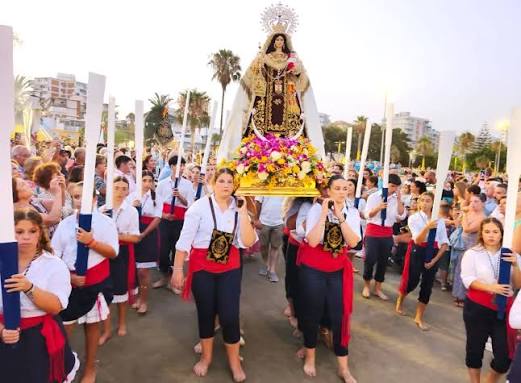 Procesión religiosa popular en un pueblo costero de Cantabria, ambiente de fiesta patronal con gente en la calle