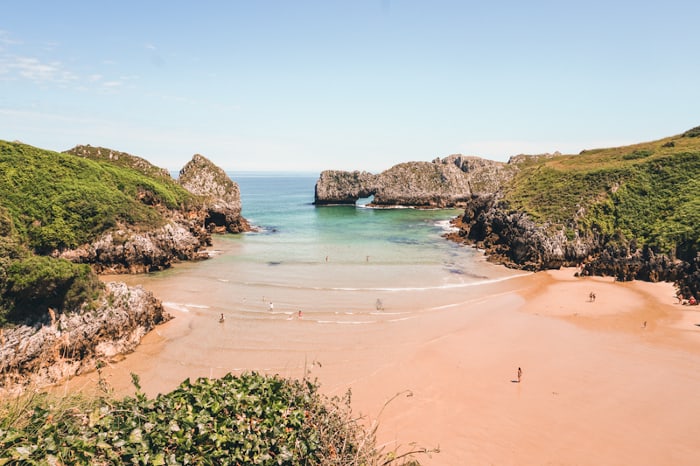 Playa de Berellín casi vacía en septiembre, marea baja, rocas kársticas expuestas, luz de tarde.
