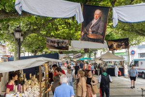 Puesto de artesanía con productos de cuero y cerámica en el Mercado Napoleónico de Torrelavega, gente paseando entre los puestos