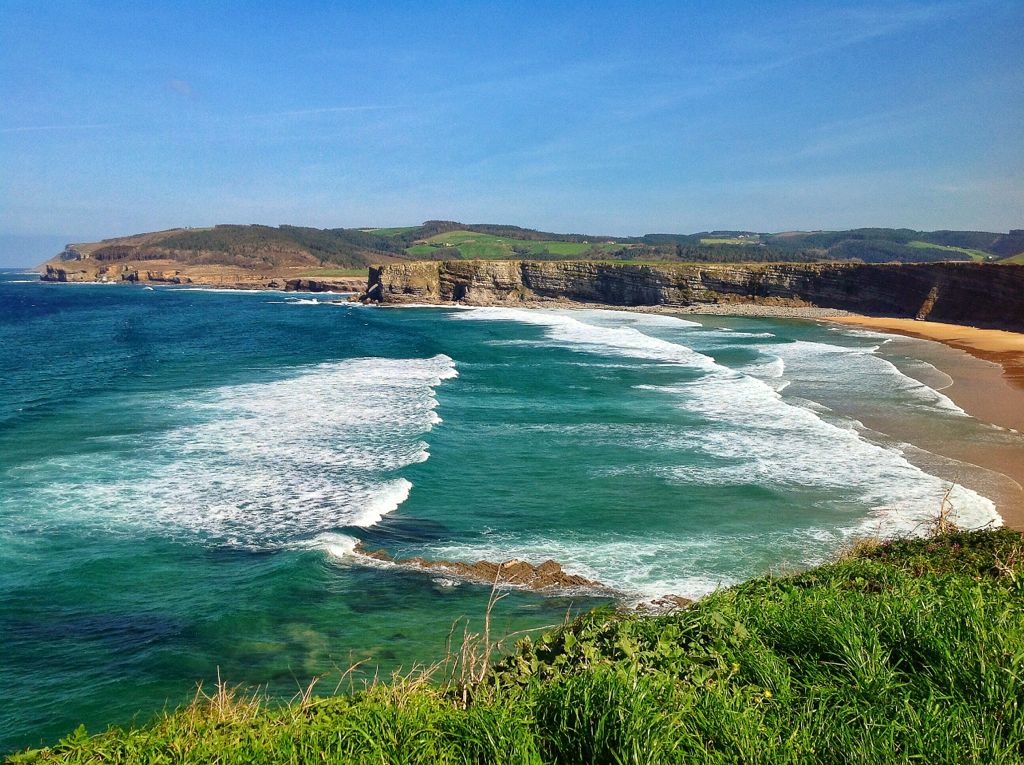 Vista panorámica de la costa occidental de Cantabria, playa amplia con dunas verdes, luz de última hora de la tarde