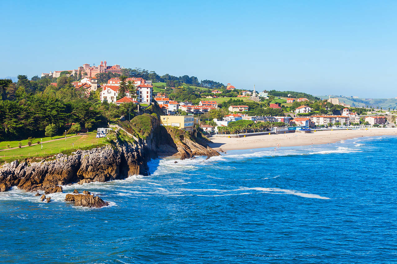 Playa de Comillas en forma de concha, con el pueblo y su arquitectura modernista al fondo