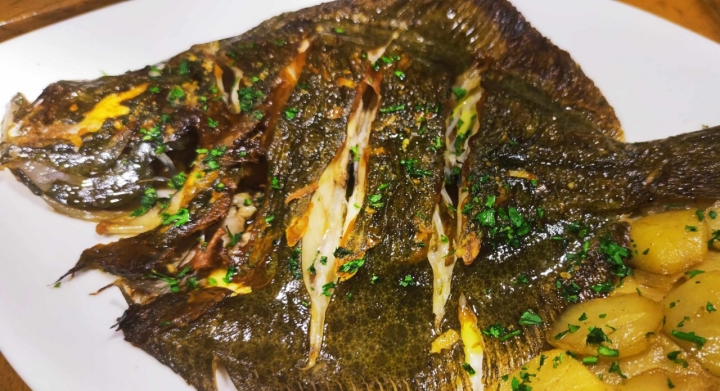 Plato de pescado a la plancha en El Restaurante de Pilar con el puerto de Santoña de fondo