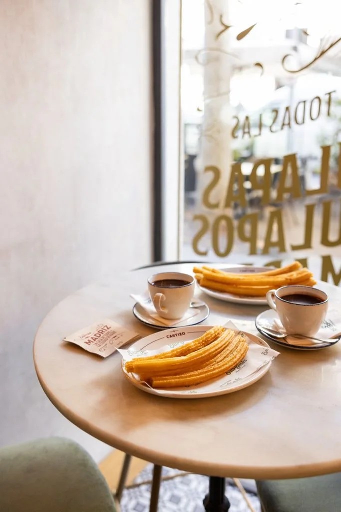 Niños merendando chocolate con churros en la terraza de una cafetería cántabra
