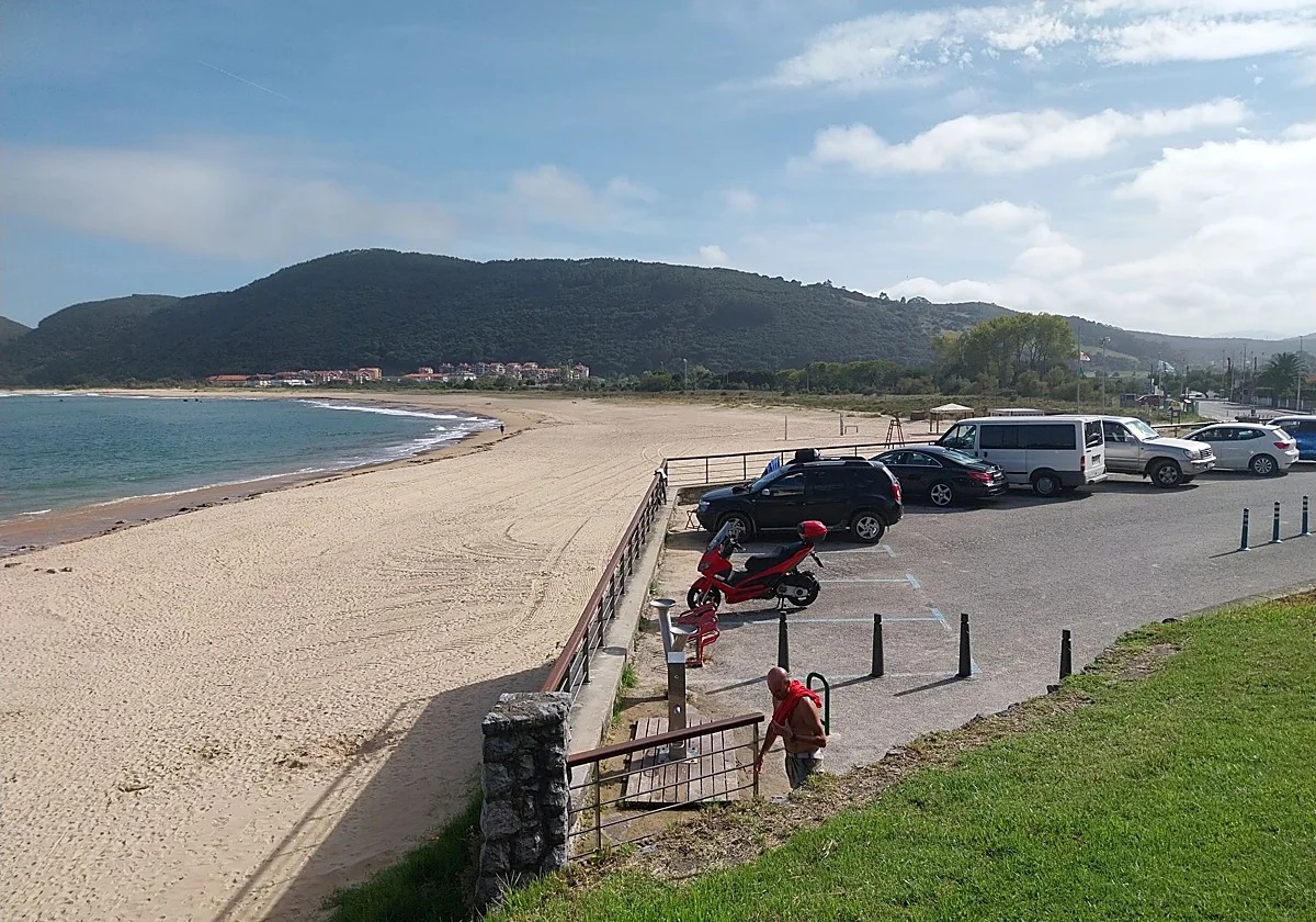 Hamacas y sombrillas alquiladas alineadas en la arena de una playa cántabra, con bares del paseo al fondo