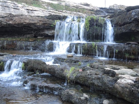 Cascada de agua dulce cayendo directamente sobre un acantilado y el mar Cantábrico, con prados verdes alrededor (Cascada del Bolao, Cóbreces).