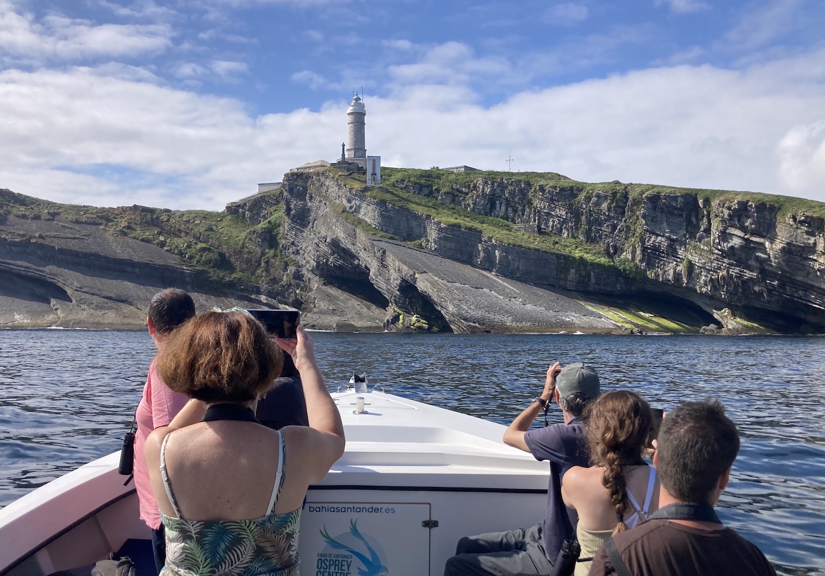 Barco de la ruta de ecoturismo navegando junto a los acantilados de la Costa Quebrada