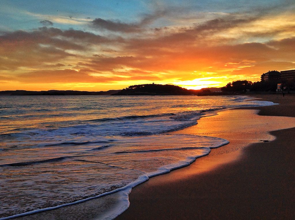 Atardecer sobre la Bahía de Santander visto desde el paseo marítimo, con un pescador en primer plano