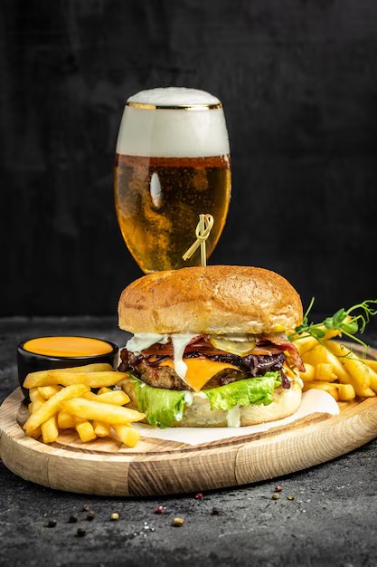 Hamburguesa gourmet smash con queso fundido, patatas fritas y cerveza artesana sobre mesa de madera al aire libre