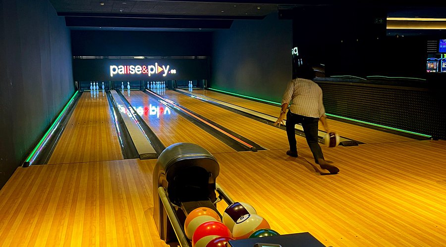 Interior de una bolera familiar con niños lanzando una bola por la pista
