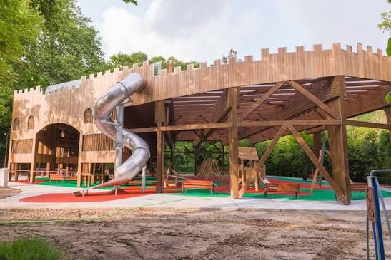 Estructura cubierta en forma de castillo del parque infantil de La Robleda en Puente San Miguel, con niños subiendo por los toboganes
