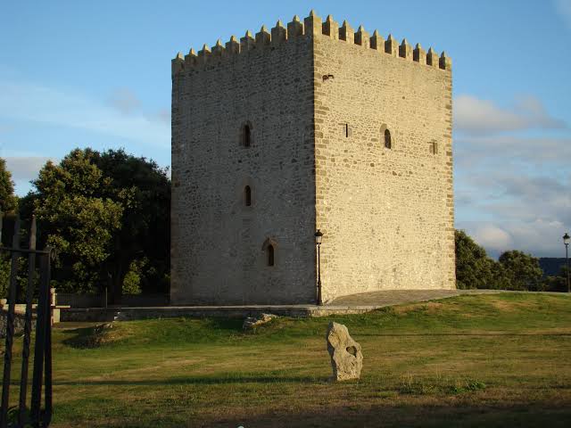 Torre defensiva cuadrada de mampostería del siglo XIV junto a una iglesia gótica en el pueblo de Castillo, Arnuero