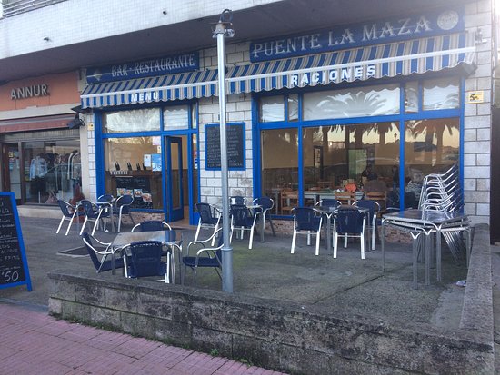 Terraza de Restaurante Puente La Maza con el puente de arcos de San Vicente de la Barquera de fondo.